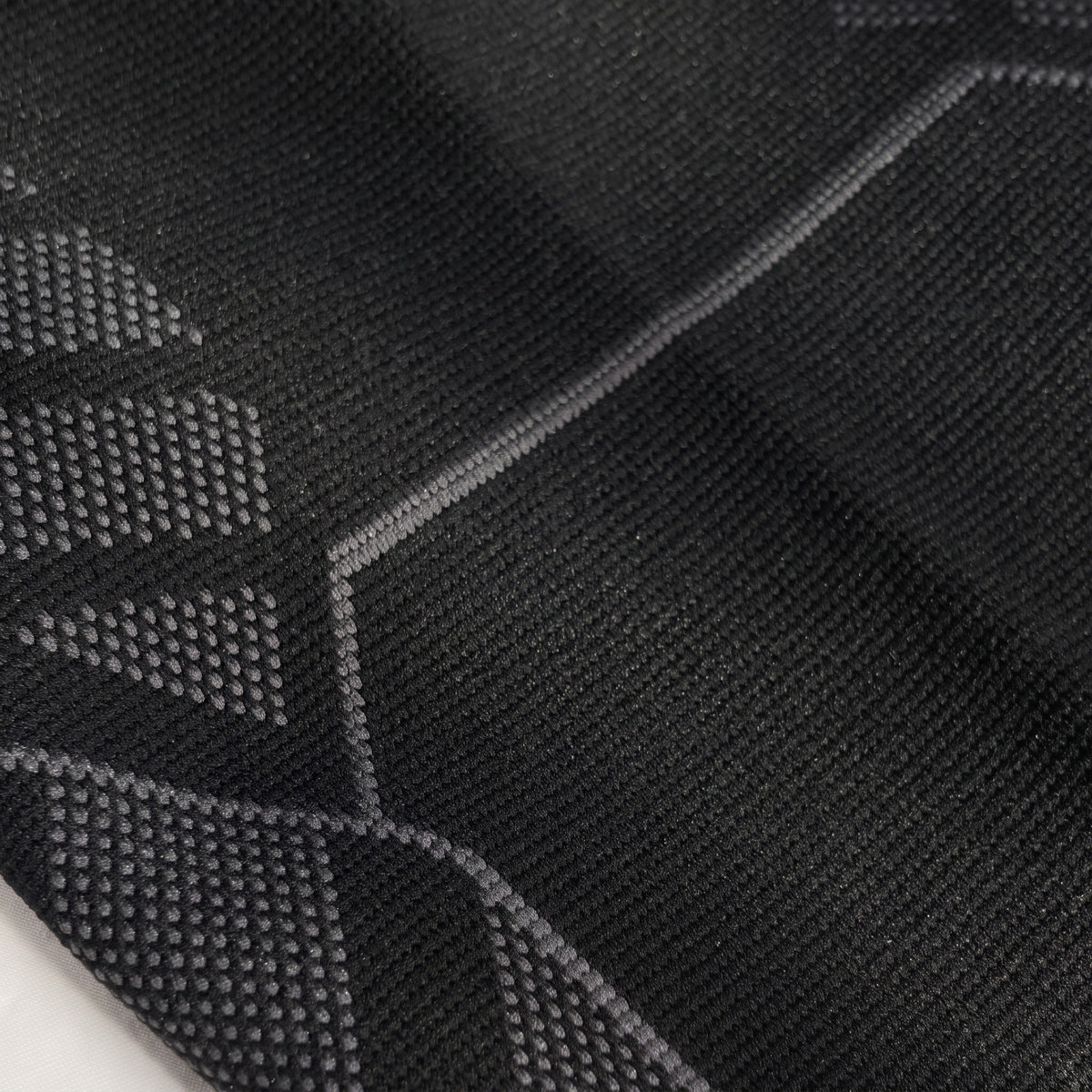 Close-up of the knee panel: hexagon-textured knit with fanned support stripes