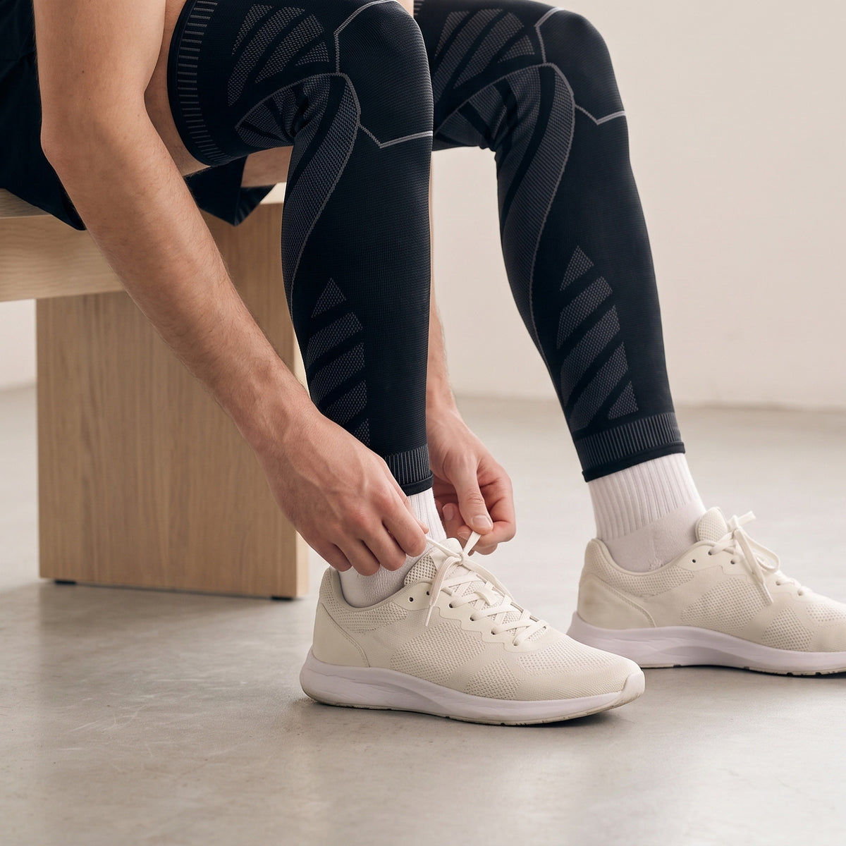Athlete on a bench lacing a trainer after a session, wearing MotionKnit compression leg sleeves